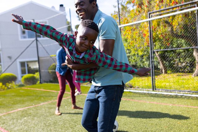 Happy African American Father Holding Son Playing In The Garden