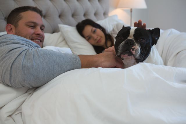 Couple petting their pet dog in bedroom - Download Free Stock Photos Pikwizard.com