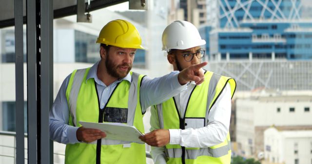 Caucasian man and young biracial man review plans on a construction site - Download Free Stock Photos Pikwizard.com