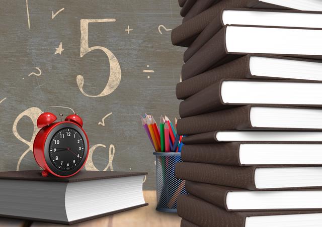 Alarm clock on a book with number and mathematical symbols on chalkboard in background