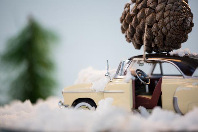 Toy car carrying pine cone on fake snow - Download Free Stock Photos Pikwizard.com
