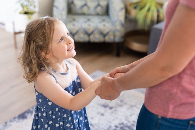Caucasian girl spending time with mom standing in living room holding hands - Download Free Stock Photos Pikwizard.com