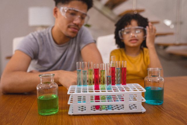 Hispanic father and son looking at chemical solutions in test tubes and beakers - Download Free Stock Photos Pikwizard.com