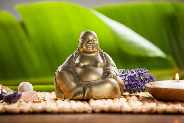 Laughing buddha figurine, lit candle and pebbles stone - Download Free Stock Photos Pikwizard.com