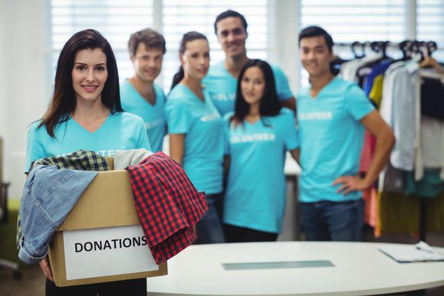 Female volunteer holding clothes in donation box - Download Free Stock Photos Pikwizard.com