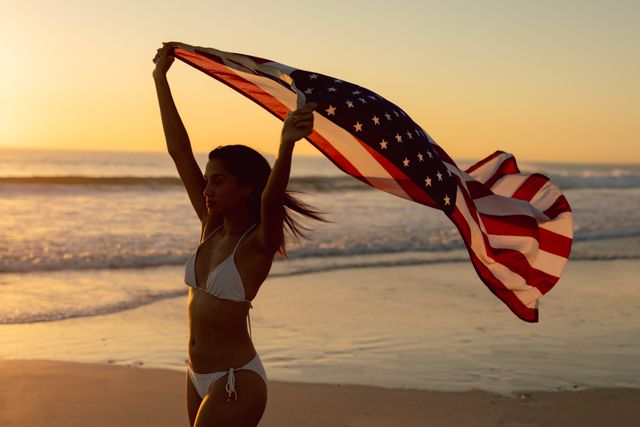 Woman standing with waving American flag on the beach - Download Free Stock Photos Pikwizard.com