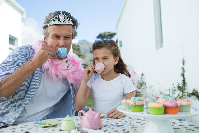 Father and daughter in fairy costume having a tea party at garden