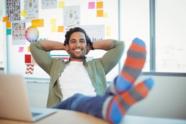 Male graphic designer relaxing with feet up at desk - Download Free Stock Photos Pikwizard.com