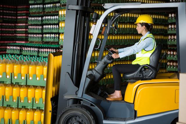 Confident female worker driving forklift in warehouse - Download Free Stock Photos Pikwizard.com