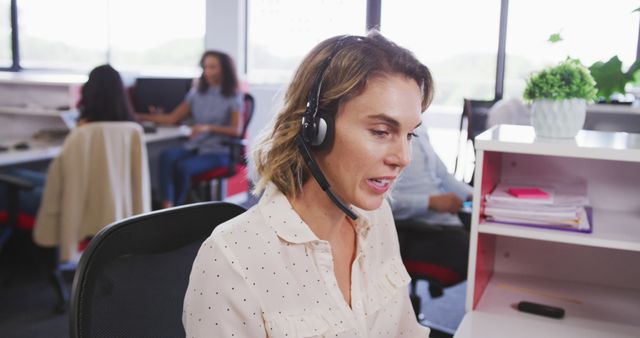 Caucasian businesswoman sitting at desk and using phone headset at office. Business, communication and work.