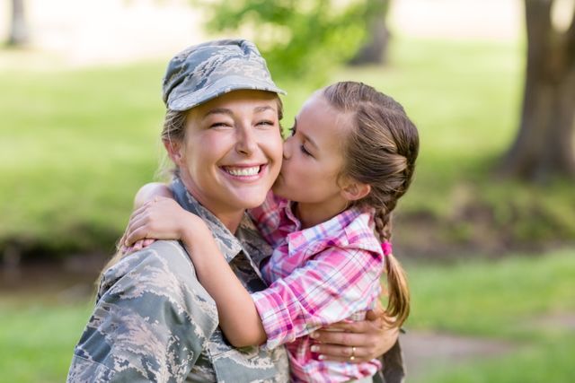 Happy female soldier being kissed by her daughter in park - Download Free Stock Photos Pikwizard.com