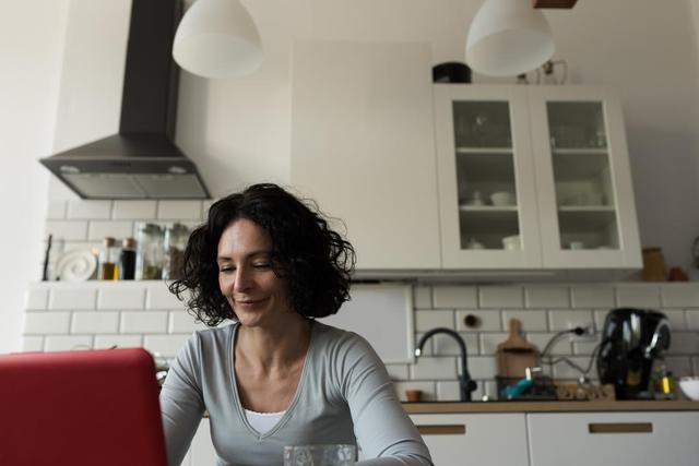 Woman using laptop in kitchen at home - Download Free Stock Photos Pikwizard.com