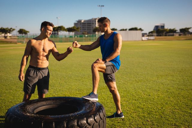 Two fit caucasian men standing at tire, fist bumping outdoors - Download Free Stock Photos Pikwizard.com