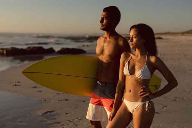 Couple standing together with surfboard on the beach - Download Free Stock Photos Pikwizard.com