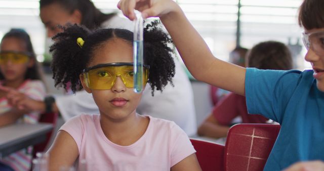 Diverse race schoolchildren wearing protective glasses holding test-tube during chemistry class. children at primary school.