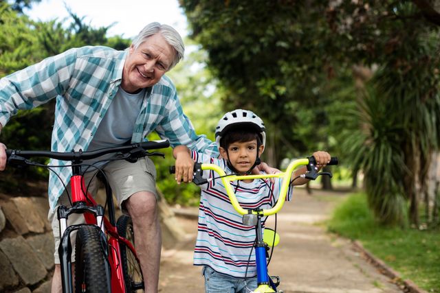 Portrait of grandfather and grandson standing with bicycle in park - Download Free Stock Photos Pikwizard.com