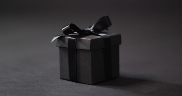 Black gift box with black ribbon on dark grey background with copy space - Download Free Stock Photos Pikwizard.com