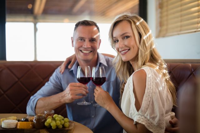 Happy couple holding wine glass while having meal - Download Free Stock Photos Pikwizard.com
