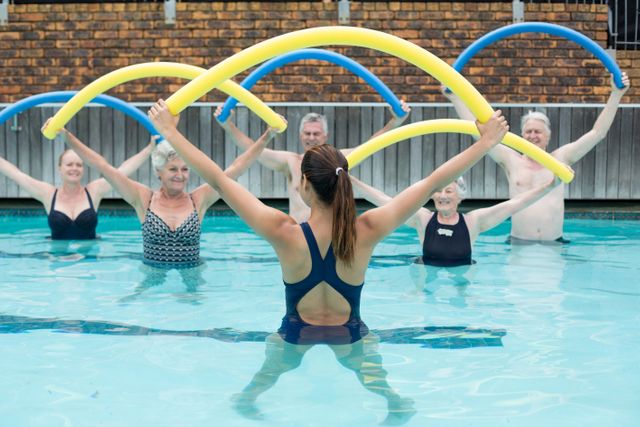 Instructor and senior swimmers exercising with pool noodle - Download Free Stock Photos Pikwizard.com