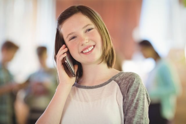 Smiling schoolgirl talking on mobile phone in corridor - Download Free Stock Photos Pikwizard.com