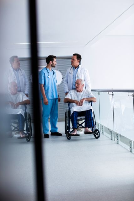 Doctors interacting with each other with patient on wheelchair in passageway at hospital