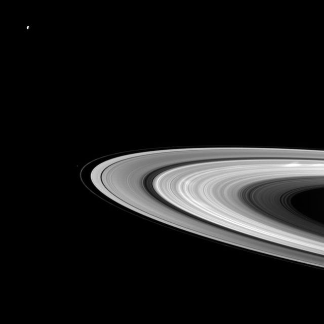 Bright spokes grace Saturn B ring in this Cassini spacecraft snapshot that also features a couple of the planet moons large and small. Dione can be seen in the upper left of the image while Pandora appears as a small speck beyond the thin F ring.