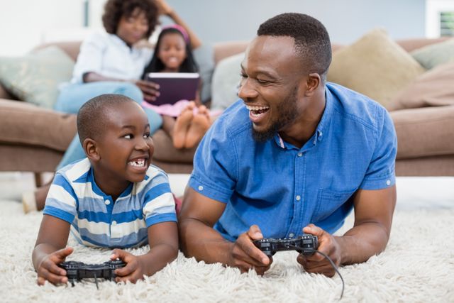 Father and son lying on rug and playing video game - Download Free Stock Photos Pikwizard.com