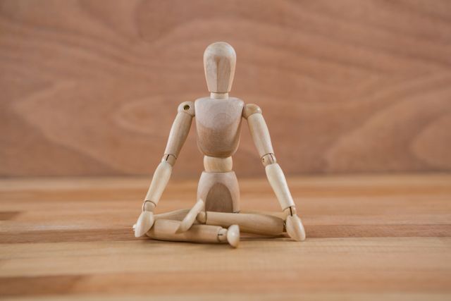 Wooden figurine sitting in a lotus position - Download Free Stock Photos Pikwizard.com