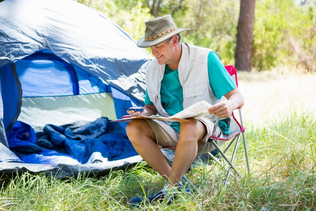 senior man reading beside his tent - Download Free Stock Photos Pikwizard.com