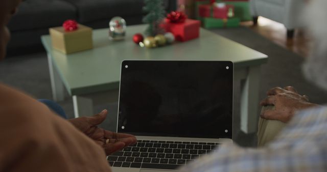 Image of african american senior couple using laptop with copy space on screen at christmas time. christmas, festivity and communication technology.