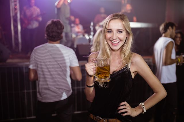 Portrait of smiling woman holding beer mug at nightclub - Download Free Stock Photos Pikwizard.com