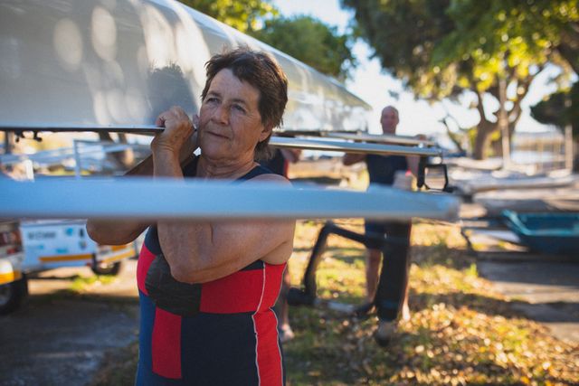 Senior caucasian woman from rowing club carrying boat on her shoulder to the river - Download Free Stock Photos Pikwizard.com