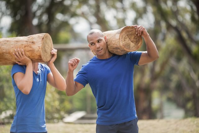 People carrying heavy wooden logs during obstacle course in boot camp