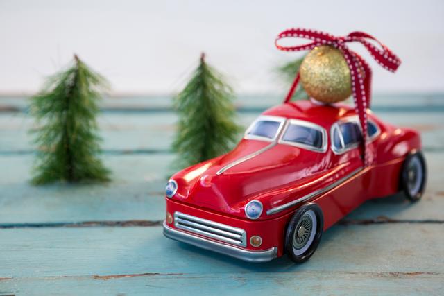 Toy car carrying christmas bauble ball on wooden plank - Download Free Stock Photos Pikwizard.com