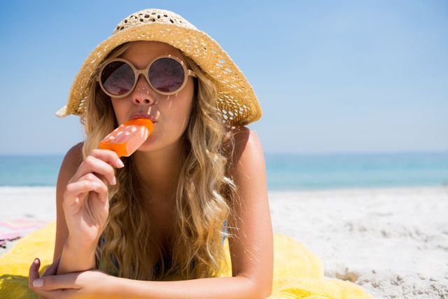 Portrait of beautiful woman eating popsicle while relaxing at beach - Download Free Stock Photos Pikwizard.com