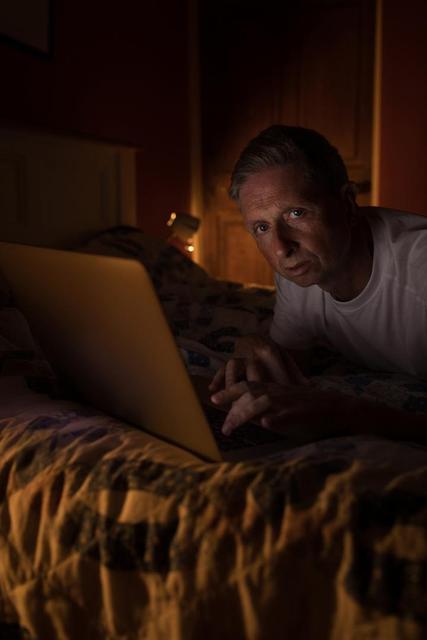 Senior man using laptop in bedroom at home