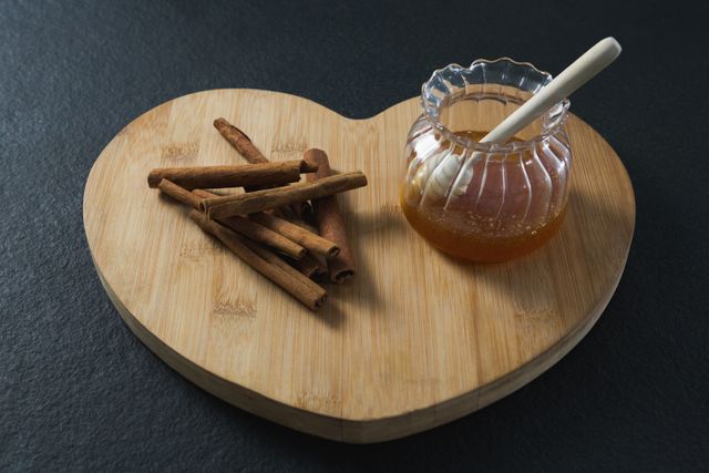 Cinnamon sticks and honey on heart shaped chopping board - Download Free Stock Photos Pikwizard.com
