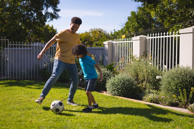 Full length of hispanic father and son playing soccer at backyard on sunny day - Download Free Stock Photos Pikwizard.com