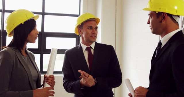 Diverse professionals in hard hats discuss construction or engineering matters. - Download Free Stock Photos Pikwizard.com