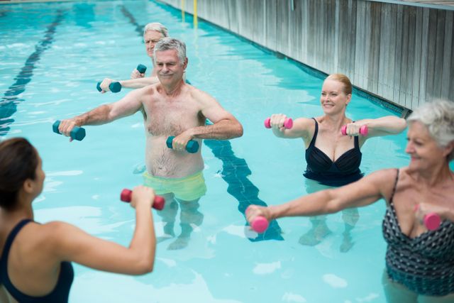 Senior swimmers and instructor lifting dumbbells in swimming pool - Download Free Stock Photos Pikwizard.com