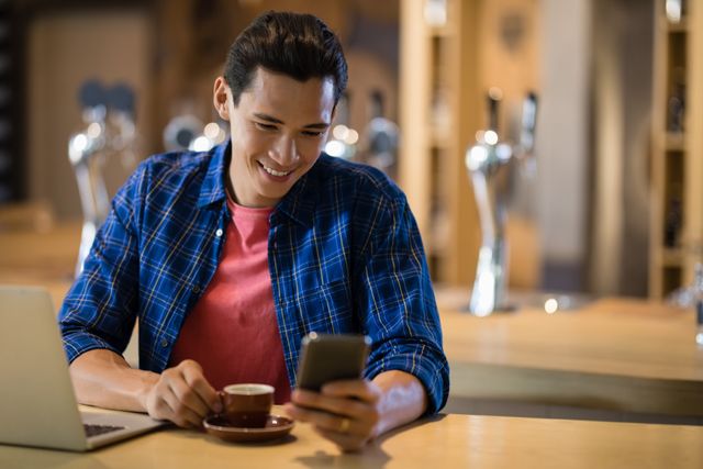 Smiling man using mobile phone in restaurant