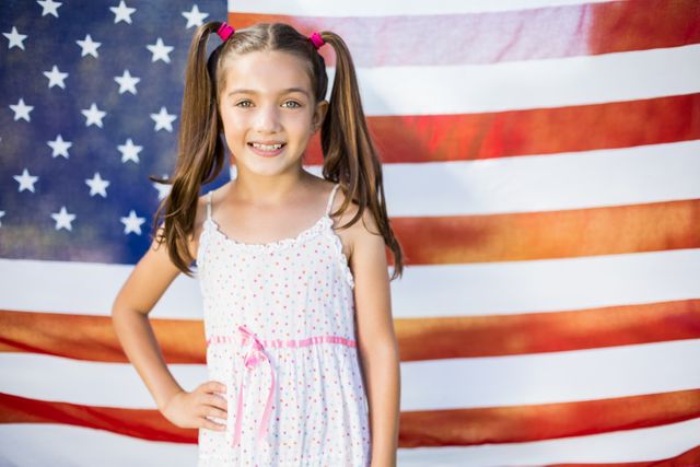 Portrait of young girl standing in front of American flag