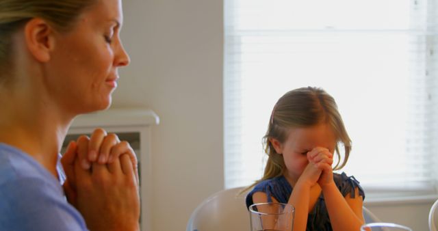 A mother and daughter share a prayerful moment at their dining table with eyes closed. - Download Free Stock Photos Pikwizard.com