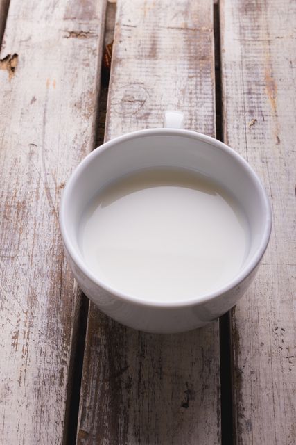 Close-up of milk in cup on white wooden table, copy space - Download Free Stock Photos Pikwizard.com
