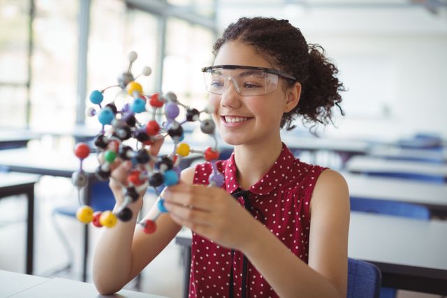 Happy schoolgirl holding experimenting model in laboratory - Download Free Stock Photos Pikwizard.com
