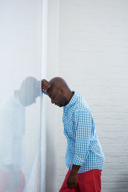 Upset man with eyes closed and hand on the forehead leaning against a wall  - Download Free Stock Photos Pikwizard.com