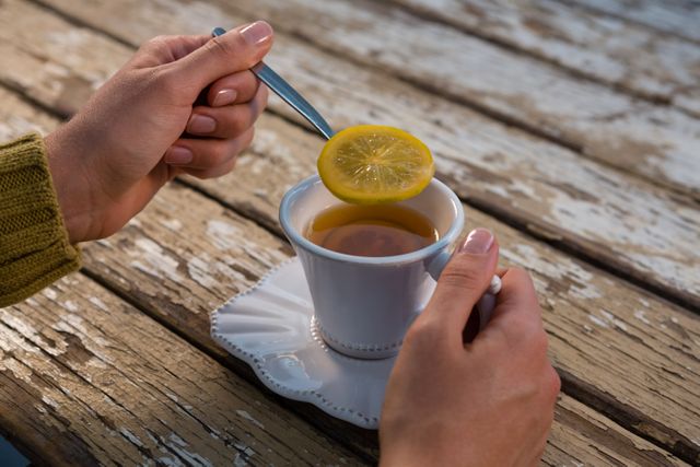 Cropped hands of woman holding lemon in spoon while having tea - Download Free Stock Photos Pikwizard.com