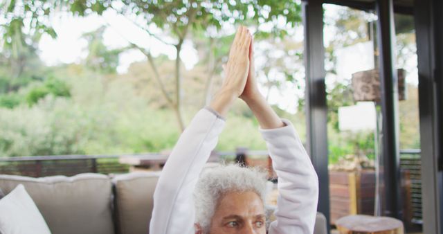 Senior mixed race woman practicing yoga, meditating. retirement and senior lifestyle, spending time alone at home.