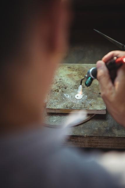 Close-up of craftswoman using blow torch in workshop