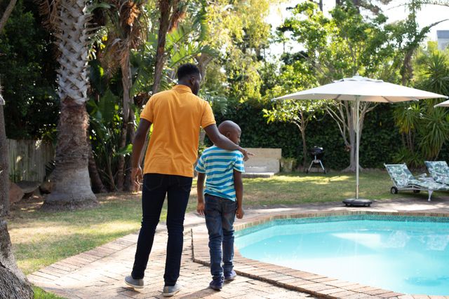 Rear view of dad and son walking by the pool - Download Free Stock Photos Pikwizard.com